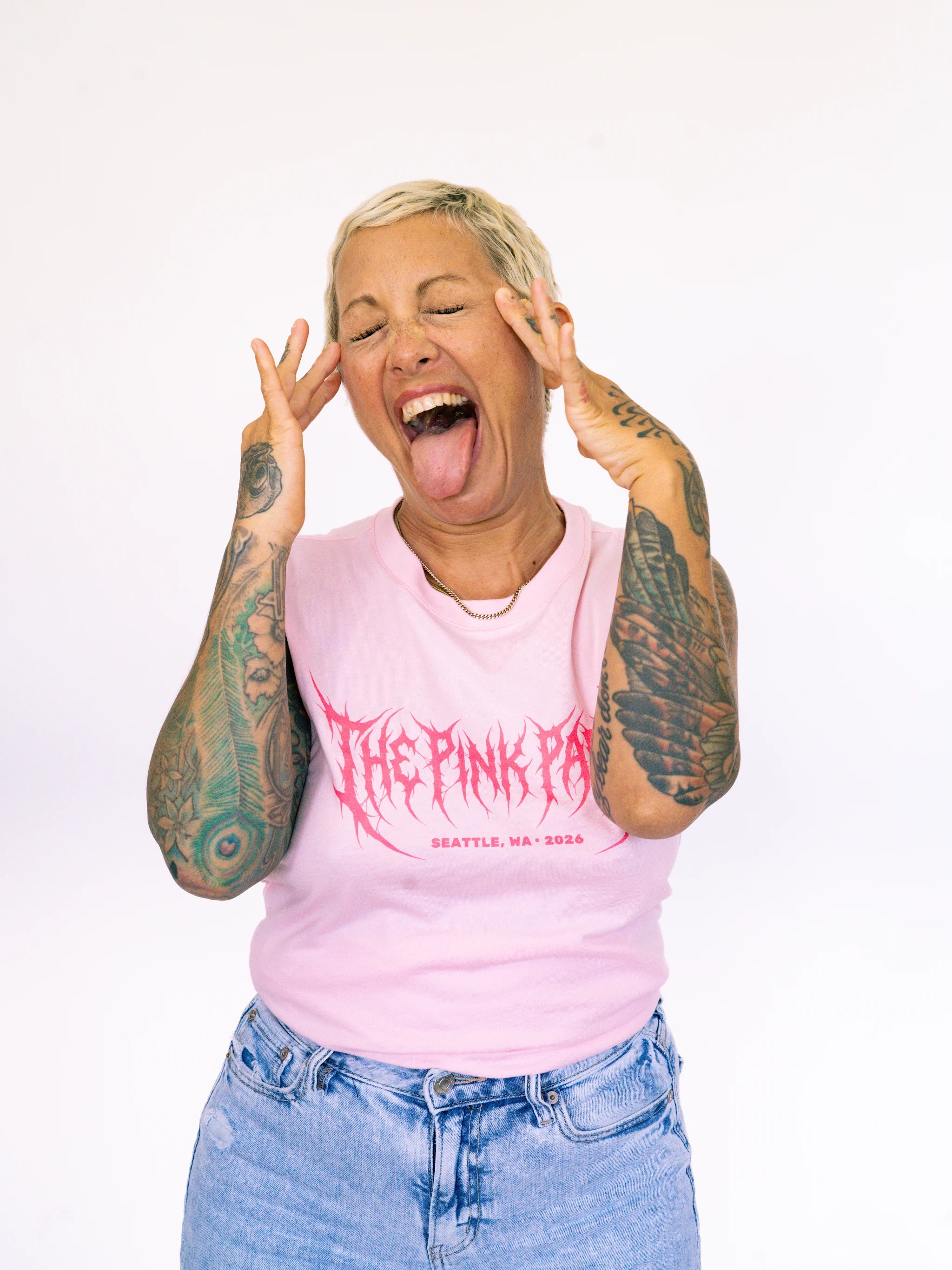 Person wearing a pink tank top with 'The Pink Pan' logo, making a peace sign gesture.