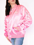 Person wearing a pink satin bomber jacket with a logo on a white background