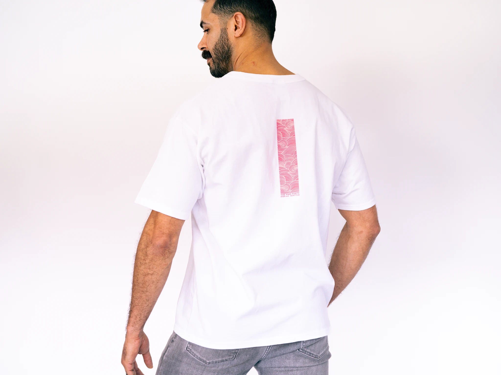 Man wearing a white t-shirt with a red square design on a plain background