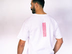 Man wearing a white t-shirt with a pink rectangle on the back against a plain background