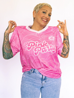 Person wearing a pink 'The Pink Party' shirt with a white background
