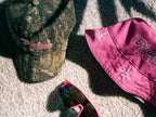 Two hats and a pair of sunglasses on a textured surface