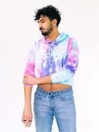Person wearing a tie-dye hoodie and jeans on a white background