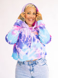 Person wearing a tie-dye hoodie with a plain background