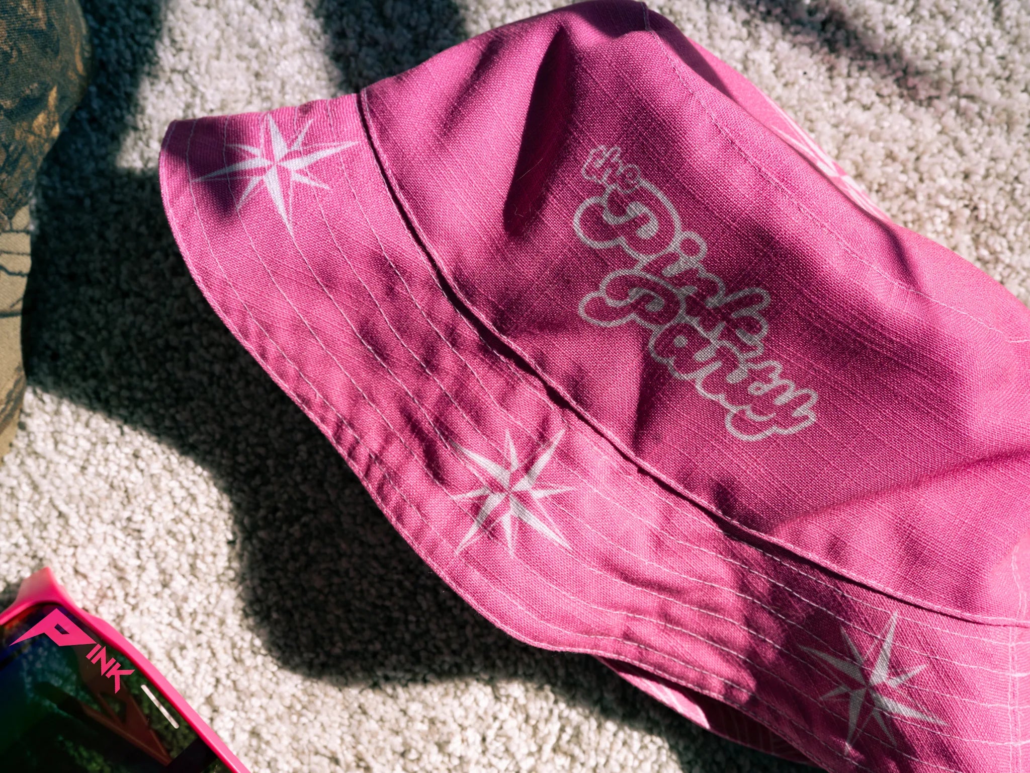 Pink bucket hat with white star designs and text on a textured surface