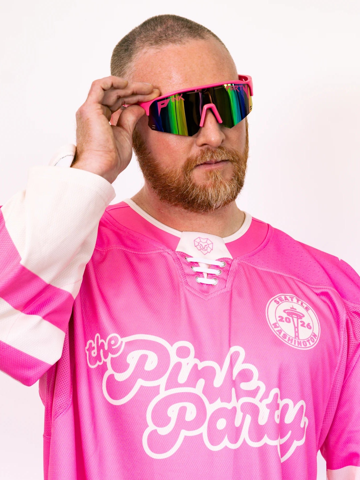 Person wearing a pink hockey jersey with 'the Pink Party' text, holding colorful sunglasses.