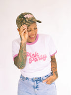 Person wearing a white t-shirt with 'Pink Party' text, camouflage cap, and denim shorts on a white background