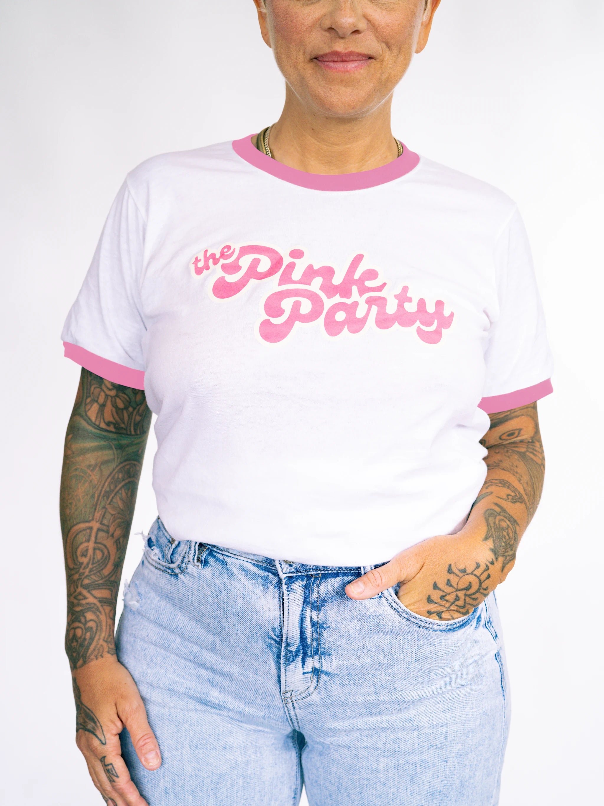 Person wearing a white t-shirt with pink trim and 'the Pink Party' text, paired with light blue jeans.