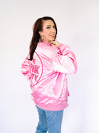 Woman in a pink satin bomber jacket with 'The Pink Party' embroidery on the back.